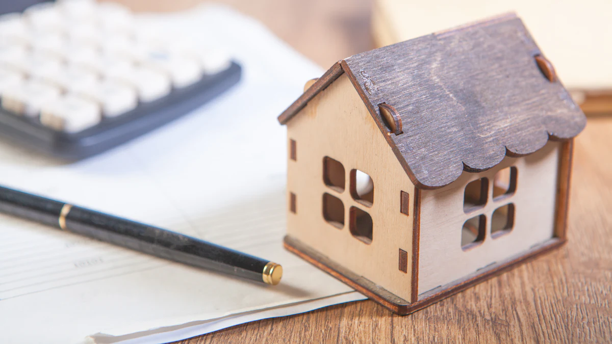 A small wooden model house beside a calculator, a pen and paperwork on a wooden desk